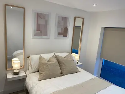 a bedroom with a white bed with two mirrors at Seaporth Studio St Ives in St Ives