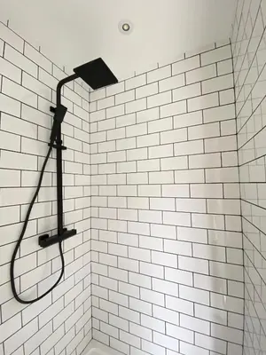a shower with a black shower head on a white tile wall at Seaporth Studio St Ives in St Ives