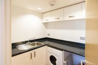 a kitchen with a sink and a washing machine at Fistral Beach Garden Apartment 3 in Newquay