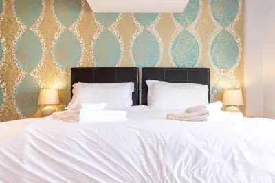 a white bed with two towels on top of it at Fistral Beach Garden Apartment 3 in Newquay