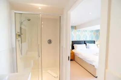 a bathroom with a shower and a bed and a tub at Fistral Beach Garden Apartment 3 in Newquay