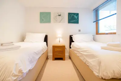 two twin beds in a room with a night stand at Fistral Beach Garden Apartment 3 in Newquay