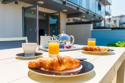 a table with a breakfast of croissants and orange juice at Fistral Beach Garden Apartment 3 in Newquay