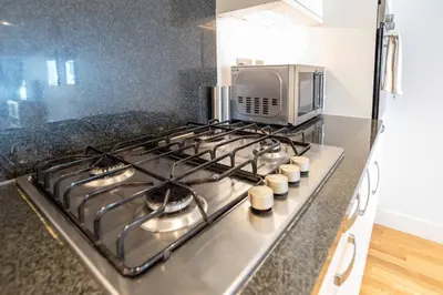 a kitchen with a stove top with a microwave at Fistral Beach Garden Apartment 3 in Newquay
