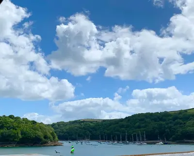 a person standing on the shore of a lake with boats at The Old Bakery in Fowey