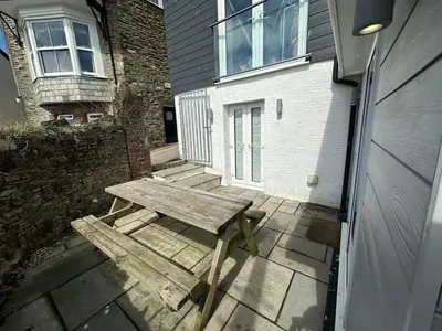 a wooden bench sitting on a patio in front of a house at Crimpers Cottage in Fowey