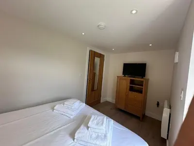 a bedroom with a bed and a television on a dresser at Crimpers Cottage in Fowey