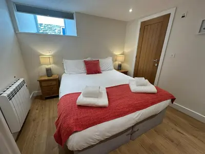 a bedroom with a large bed with two towels on it at Crimpers Cottage in Fowey