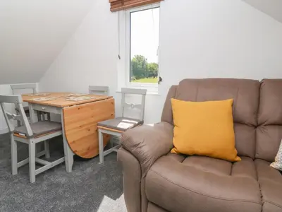 a couch with a yellow pillow sitting next to a desk at Little Valley View in Hayle