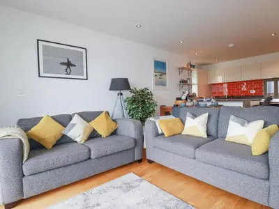 a living room with two gray couches and yellow pillows at Crantock Reach in Newquay