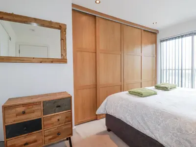a bedroom with a bed and a dresser and a mirror at Crantock Reach in Newquay