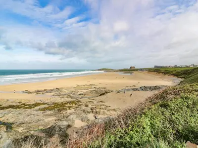a beach with people on the sand and the ocean at Crantock Reach in Newquay