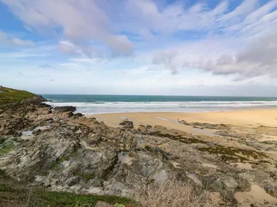 a sandy beach with people walking on the beach at Crantock Reach in Newquay
