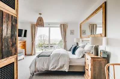 a bedroom with a large bed with a large mirror at The Gate Cornwall in Looe