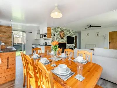 a dining room and kitchen with a wooden table and chairs at By The Beach- Uk31201 in Downderry