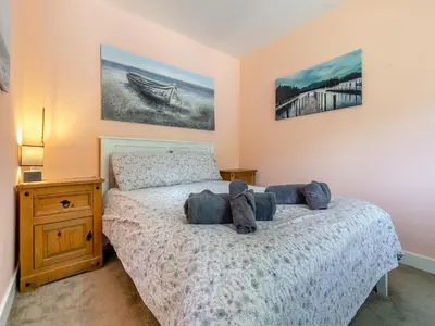 a bedroom with a bed and a wooden nightstand at By The Beach- Uk31201 in Downderry
