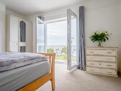 a bedroom with a bed and a door to a balcony at On The Beach, East Yardley House - Uk31203 in Downderry