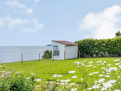 a small white house in a field of flowers at On The Beach, East Yardley House - Uk31203 in Downderry