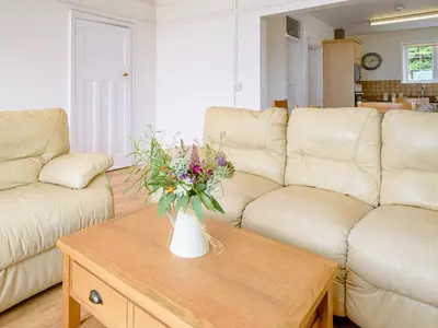 a living room with a vase of flowers on a coffee table at On The Beach, East Yardley House - Uk31203 in Downderry