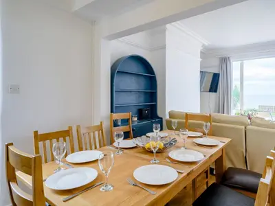 a dining room with a wooden table with plates and wine glasses at On The Beach, East Yardley House - Uk31203 in Downderry