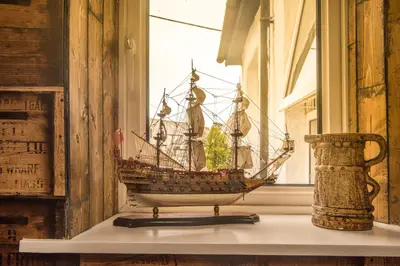 a model ship on a shelf in a window at Deluxe Pirate's Cove Themed Apartment in St Austell