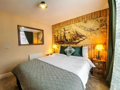 a bedroom with a large bed and a painting on the wall at Deluxe Pirate's Cove Themed Apartment in St Austell