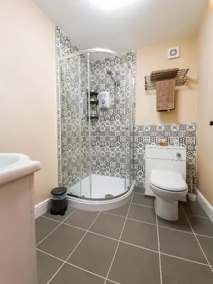 a bathroom with a shower and a toilet and a sink at Deluxe Pirate's Cove Themed Apartment in St Austell