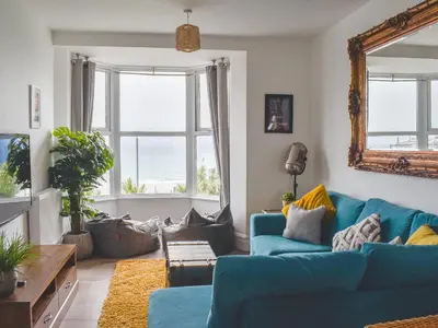 a living room with a blue couch and windows at Beach View in Newquay
