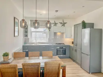 a kitchen with a table with chairs and a refrigerator at Beach View in Newquay
