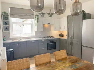 a kitchen with blue cabinets and a table with chairs at Beach View in Newquay