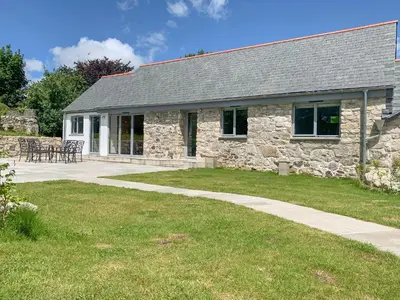 a stone building with a table and chairs in front of it at The Corn Store in St Austell