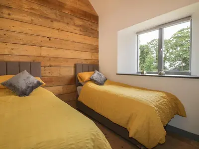two beds in a room with wooden walls at The Corn Store in St Austell