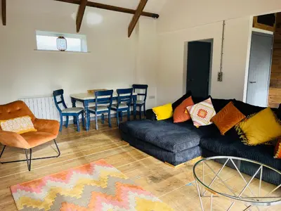 a living room with a couch and a table and chairs at The Corn Store in St Austell