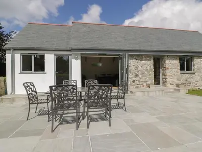 a patio with chairs and a table in front of a building at The Corn Store in St Austell