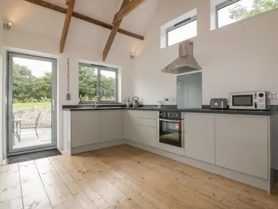 a kitchen with white cabinets and a stove top oven at The Corn Store in St Austell