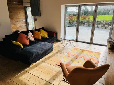 a living room with a black couch and a glass table at The Corn Store in St Austell