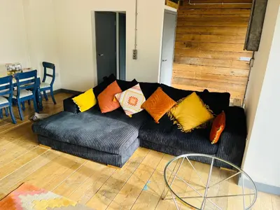 a black couch with colorful pillows in a living room at The Corn Store in St Austell