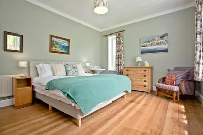 a bedroom with a bed and a chair at Cregoes, Mylor - Bungalow - Riverview - Free Parking & WiFi - Pet friendly in Flushing