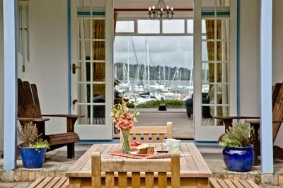 a porch with a table with flowers in a vase at Cregoes, Mylor - Bungalow - Riverview - Free Parking & WiFi - Pet friendly in Flushing