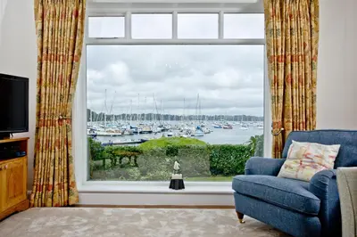 a living room with a window with a view of a harbor at Cregoes, Mylor - Bungalow - Riverview - Free Parking & WiFi - Pet friendly in Flushing