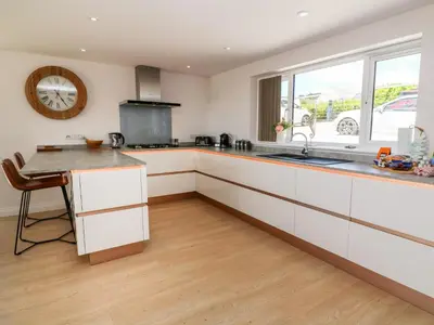 a kitchen with white cabinets and a sink and a table at Atlantic View in Penzance