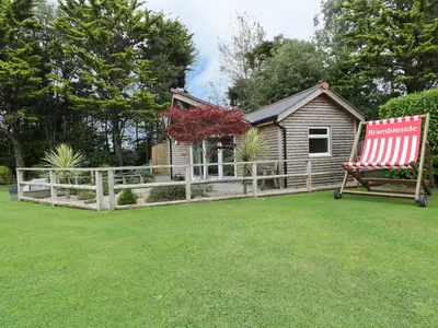 a house with a fence and a red chair in a yard at Brambleside Lodge in Truro