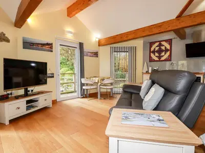 a living room with a black leather couch and a television at Brambleside Lodge in Truro