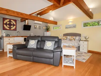 a living room with a couch and a kitchen at Brambleside Lodge in Truro