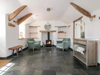 a living room with a fireplace and two chairs at Harbour Cottage in Boscastle