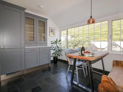 a kitchen with a table and chairs and windows at Harbour Cottage in Boscastle