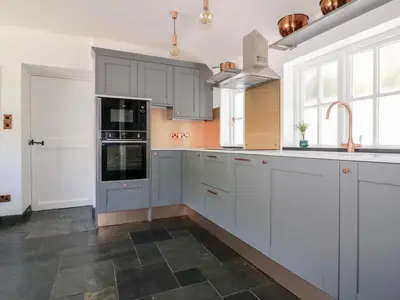 a kitchen with gray and white cabinets and appliances at Harbour Cottage in Boscastle
