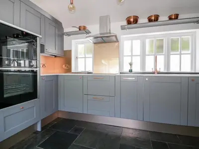 a kitchen with white cabinets and a stove at Harbour Cottage in Boscastle