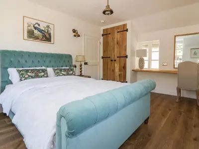 a bedroom with a blue bed and a desk at Harbour Cottage in Boscastle