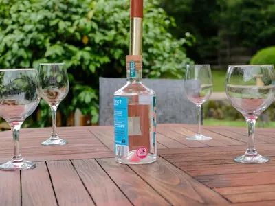 a bottle of wine sitting on a table with four wine glasses at Lantern Cottage in St Austell
